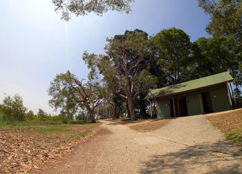 Road amidst trees and buildings against sky