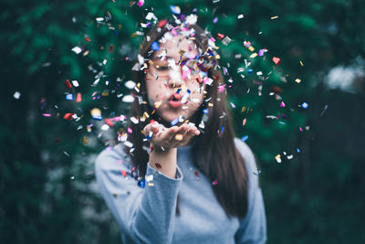 Young woman blowing confetti outdoors