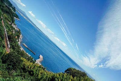 High angle view of sea and mountains against blue sky