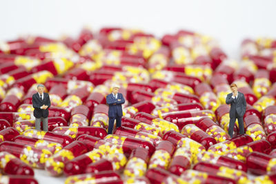 Miniature people with medical drug capsule on white background