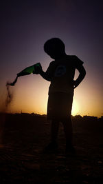 Rear view of silhouette man standing against sky during sunset