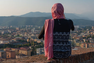 Rear view of woman looking at cityscape against sky