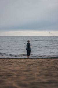 Full length of woman standing on beach against sky