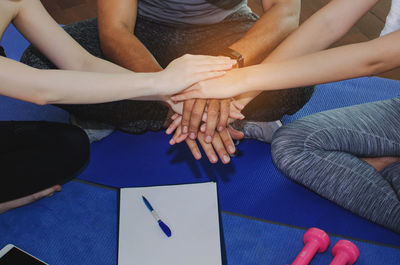 Friends stacking hands in yoga studio