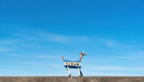 Rear view of wooden lamp standing at the wall against clear sky