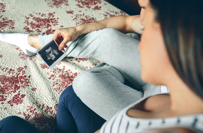 Midsection of woman using mobile phone while sitting on sofa at home