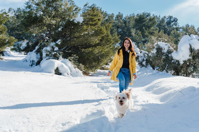 Woman with dog on snowcapped mountain against sky