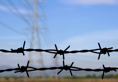 Two barbed wire silhouette with blurred high voltage post background