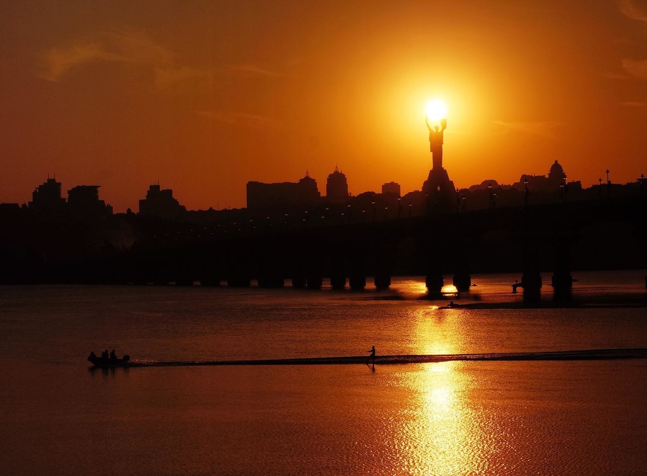 sunset, silhouette, water, sun, orange color, architecture, building exterior, built structure, sky, river, waterfront, outdoors, travel destinations, nautical vessel, nature, city, scenics, beauty in nature, no people, skyscraper, cityscape, day