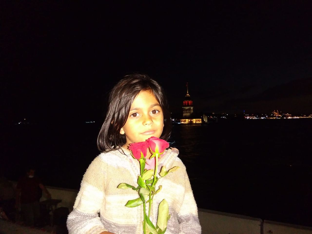 PORTRAIT OF BEAUTIFUL WOMAN STANDING BY ILLUMINATED RAILING