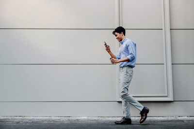 Side view of young man standing against wall