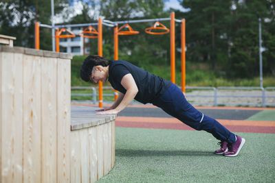 Young woman doing push-ups at outdoor gym