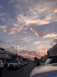 Cars on road against sky at sunset