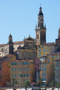 Buildings in city against clear blue sky