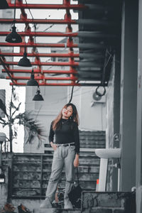 Portrait of young woman standing against building