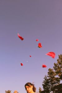 Low angle view of woman paragliding against clear blue sky