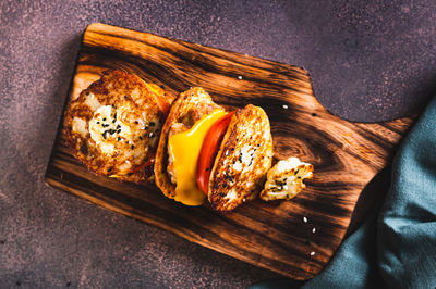 Close up of keto burgers on cauliflower fritters with cutlet, tomato and cheese on a board top view