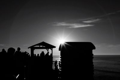 Silhouette people at beach against sky during sunset