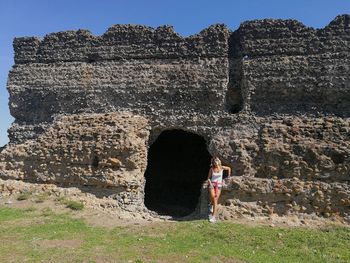 Full length of woman standing on rock against sky