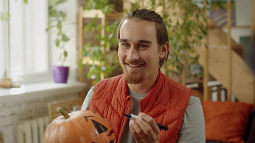 Portrait of young man holding pumpkin