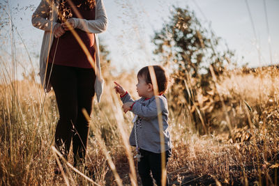 Low section of woman standing by daughter on grassy field