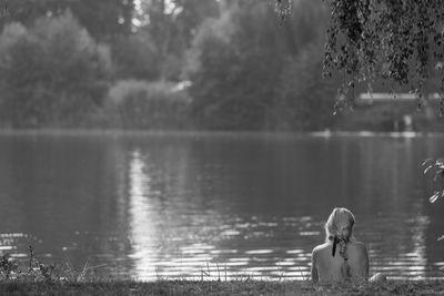 Rear view of woman standing by lake