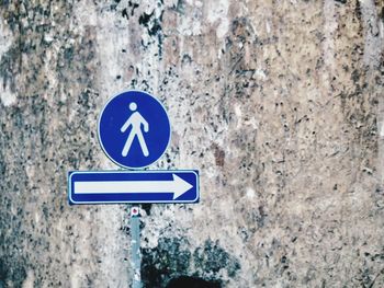 Close-up of road sign on weathered wall