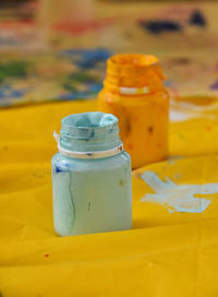 Close-up of paint bottles on paper