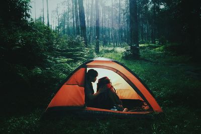 Woman sitting in a tent in forest