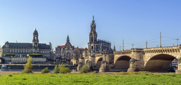 Arch bridge over buildings against clear sky