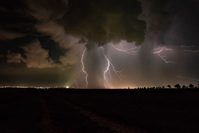 Panoramic view of lightning over landscape against storm clouds