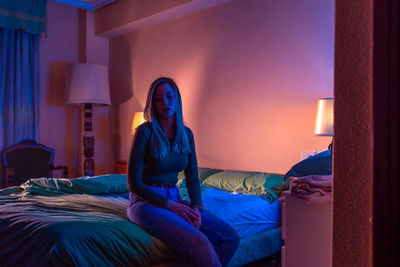 Woman sitting on bed at home