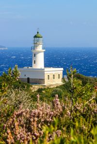 Lighthouse by sea against sky