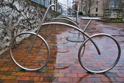 Bicycle parked by railing on street against building