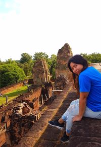 Young woman sitting on tree against clear sky