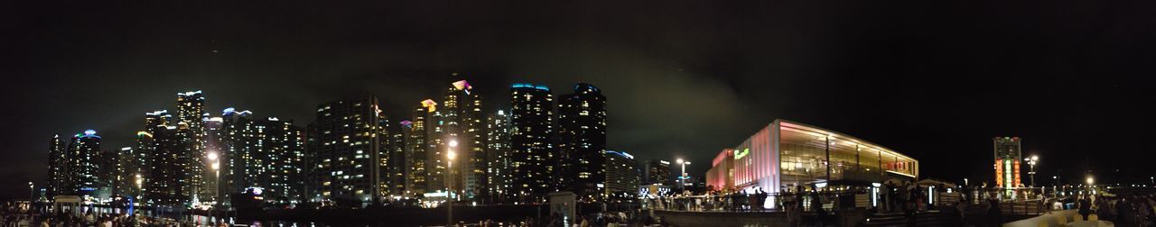 Illuminated modern buildings against sky at night