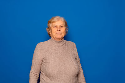 Portrait of young woman standing against blue background