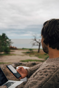 Portrait of man using mobile phone against sky