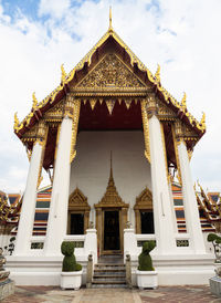 A temple building with golden roof details located inside the wat pho complex in bangkok, thailand.
