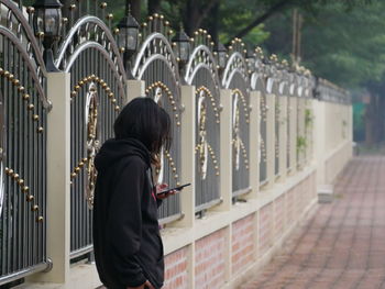 Rear view of woman standing on footpath