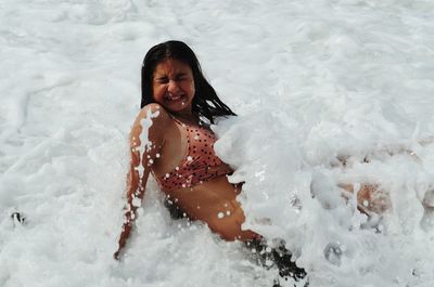 High angle view of smiling woman sitting in water at beach