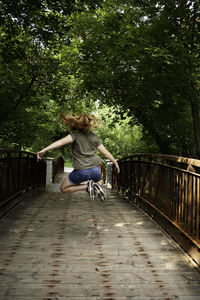 Rear view of woman riding bicycle on footpath