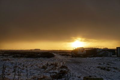 Scenic view of snow covered field at sunset