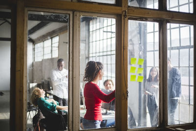 Team of computer programmers planning start-up strategy in board room seen through glass wall