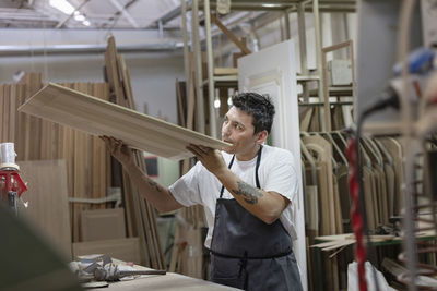 Artist examining wood while standing at workshop