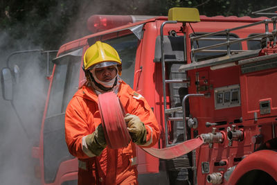 Firefighter holding hose by engine