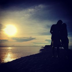 Rear view of silhouette man and woman walking at beach during sunset