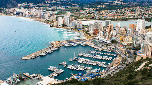 Sailboats moored at harbor by city at coastline