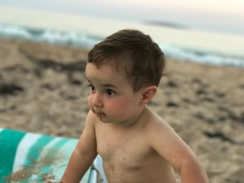 Shirtless boy on beach against sky