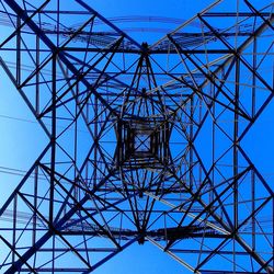 Low angle view of electricity pylon against blue sky